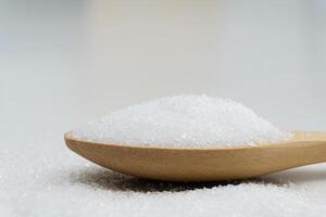 Close up scoop with white sand and lump sugar on wooden background photo