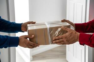 Hands exchanging cardboard box in well lit indoor setting, white background photo