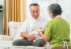 Senior couple with a cup of coffee in living room, Asian elderly couple relaxing photo