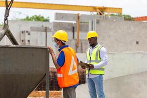 Engineer and foreman worker checking project at building site, Engineer and builders in hardhats discussing on construction site photo