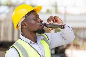 Engineer man drinking water at the precast factory site, Worker man drinking cola from a bottle on a site photo