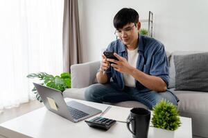 A man is sitting on a couch and looking at his cell phone photo