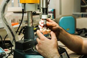 Technician working with dental mold on precision machine photo