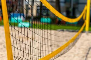 yellow volleyball net is stretched across a sandy beach photo