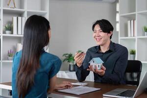 Real Estate Agent Discussion Property with Client in Modern Office Setting, Holding House Model and Keys photo