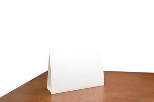 White paper sheet tent card on wooden table white isolated background can insert customer message. clipping path. Stand mockup frame menu card photo