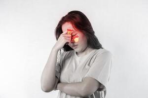 A woman with a red nose and red eyes. She has her hands on her head. Sinusitis, frontitis. photo