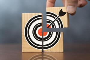 Business target concept of hand putting the jigsaw puzzle last missing piece. Close-up wooden figure, as businessman on jigsaw puzzles with target icon symbol photo