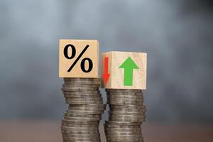 The concept of increasing or decreasing interest rates. Wooden cube with percentage icon Up and down symbols are placed on piles of coins photo