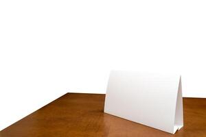 Blank paper table card on wooden table over white isolated background. Picture text can be inserted for advertising communication. photo