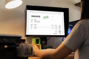 Business Invoice Tax Management. Accountant Using Monitor, studying financial business documents at her desk photo