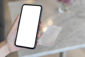 Close up woman university student holding smartphone with empty mock up copy space screen background for promotional content while sitting in coffee shop during rest in winter day. photo