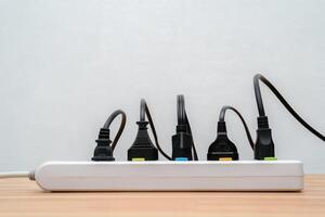 Surge protector with connected white wires of electrical appliances. Free space. Socket strip and connected plugs on background. photo