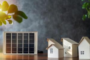 Small cardboard house and solar panels close up. Free space to put text, images, media. Close up view of alternative energy engineer pointing at solar panels photo