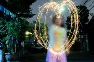 A large heart drawn out with a sparkler. Girl draws out a heart using a sparkler photo