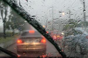 Windshield wipers from inside of car, season rain,filter color effect. Selective focus to rain droplet with motion blurry wiper photo
