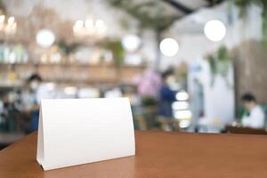Blank menu frame label mockup. Mock up menu frame on table in bar restaurant, stand for booklet with white sheet of acrylic tent card paper in blur cafeteria photo