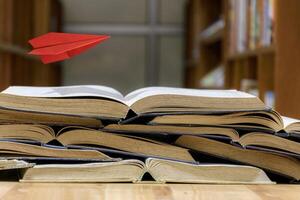 world book day flying paper plane imagination read. A paper airplane flies over a pile of old books open photo