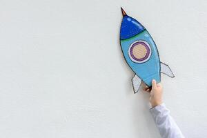 Young Asian boy holding rocket on raised hand standing in art class in backlit with imagination the astronaut and space rocket photo