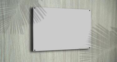 A gray picture frame hangs on the wall with wood grain wallpaper overlaid with leaf shadows for advertising purposes. photo