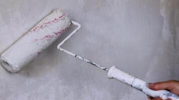 Worker hand painting wall surface with paint roller. Renovating apartment. Brush roller paints the wall with white color for protection from corrosion. Empty copy space textured background. Close up. video