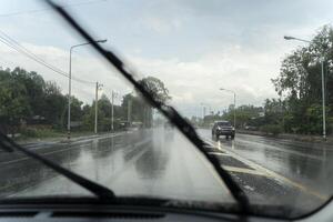 Car wipers clean windshields when driving in sunny weather, driver drives the car on a rainy day. photo
