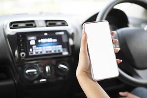 Woman using mobile smart phone, checking address location via navigator application, driving a car. Driver hand holding and looking at cellphone inside a car photo