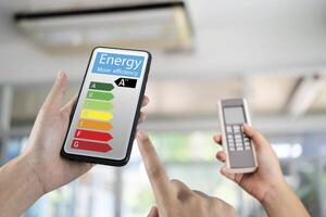 Hand holding digital smart phone and looking at house efficiency rating. Detail of house efficiency rating on digital tablet screen. Concept photo