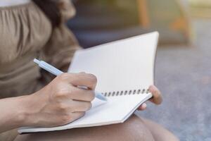 Note Taking Concept. Side view close up portrait of attractive asian woman writing in her diary, copy space photo