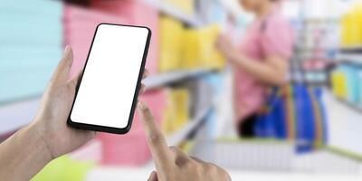 Mockup blank white screen mobile phone with finger point and touch on touchsreen with women are shopping in department stores. photo