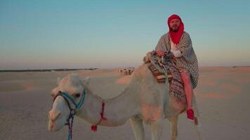 Tourist on camel in desert enjoying his ride wearing red turban. video