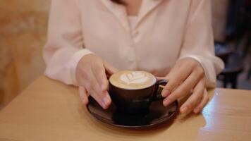 Black mug with coffee on a saucer and the woman having a sip out of it. video