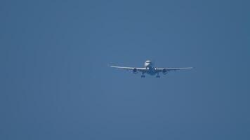 A passenger plane with an unrecognizable livery is approaching for landing, bottom view. Airliner in the blue sky. Flight arrival. Air traffic Travel concept video