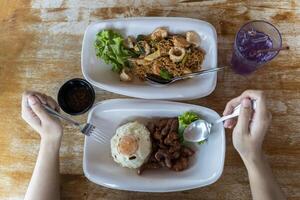 Hand holding a spoon The fork is placed on the dining table. Rice with fried pork, fried egg photo