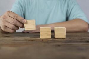 Close-up of three businessmen arranging wooden blocks Wooden toy blocks on a desk can be inserted with image text photo