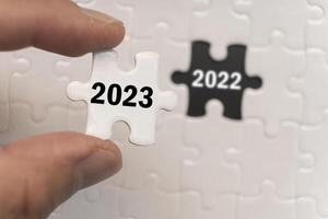 Man's hand holding a number puzzle Year 2023 The background is the year 2022 that will be replaced. happy new year concept photo