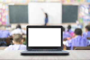 Computer on the table, blur image of children in the classroom as background. photo