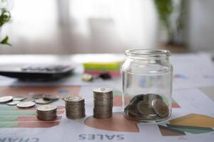 Pile of silver coins with graph paper and a calculator on a wooden table. account concept Finance and business growth photo