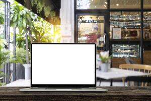 Blank screen laptop computer on wood table top with blur cafe restaurant with abstract bokeh light defocused photo