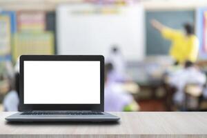 Computer on the table, blur image of the children classroom as background. photo