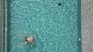 Aerial view of caucasian man swimming on his back in a pool in summer video