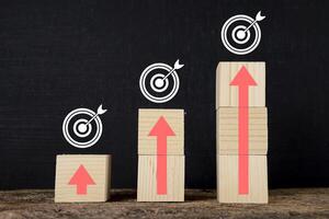 Wooden blocks stacked in steps with red arrows on the table. photo