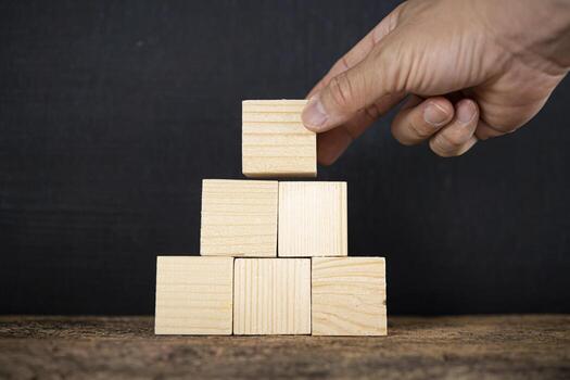 Hand putting and stacking blank wooden cubes on table with copy space for input wording and infographic icon. photo