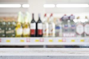 White vintage wooden table top and beautiful bokeh shelf with alcohol bottles in the background. photo