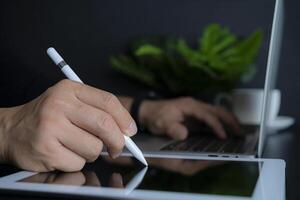 Close up of businessman using digital tablet and laptops at work. photo