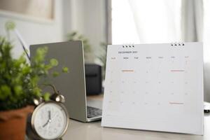 Simple desk calendar for December 2021 on workplace background. photo