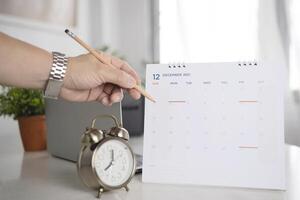 Hand holding a pencil writing on the calendar to prepare for the event in December of 2021. photo