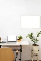 Photo of white blank screen computer laptop putting on black working desk and surrounded by stack of notebook