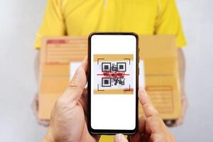 Selective focus to QR code of parcel delivery tag on smartphone to scan tag on parcel box in post office. photo