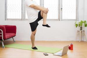 Strong Athletic Fit Man in T-shirt and Shorts is Energetically Jogging in Place at Home photo